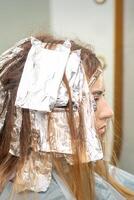 Haar foliert während Haar Färberei von ein jung Frau im Haar Salon schließen hoch. foto