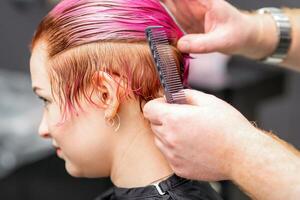 Styling weiblich Haar. männlich Friseur macht Frisur zum ein jung Frau im ein Schönheit Salon. foto