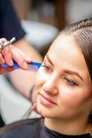 Styling weiblich Haar. männlich Friseur macht Frisur zum ein jung Frau im ein Schönheit Salon. foto