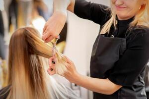 Schneiden weiblich blond Haar. Friseur schneidet Haar von ein jung kaukasisch Frau im ein Schönheit Salon schließen hoch. foto