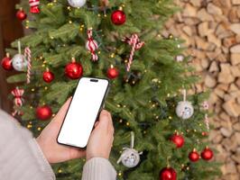 Berlin Deutschland Januar 21 2024 Weihnachten Urlaub, Hand halten Smartphone, Handy, Mobiltelefon Telefon durch Baum mit foto