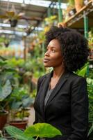 schwarz Geschäft Frau im ein Garten Center umgeben durch Grün foto