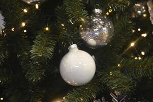 Weiß Ball auf das Geäst von ein Weihnachten Baum. festlich Neu Jahr Hintergrund. foto