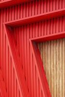 abstrakt Muster von rot gewellt Stahl mit hölzern Mauer Dekoration von modern Gebäude im Vertikale Rahmen foto