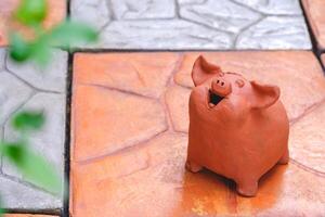 Zier Terrakotta Garten Puppe im das gestalten von wenig bezaubernd Schwein lächelnd glücklich auf Stein Fliese Pflaster Fußboden im Zuhause Garten foto
