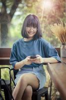 asiatischer Teenager, der ein Smartphone in der Hand hält und vor Glück lächelt