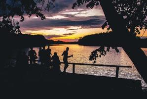 Gruppe von Freunden Silhouette am See Spaß in der Natur auf Feiern. Leerraum-Spaß-Party im Freien am Seehintergrund foto