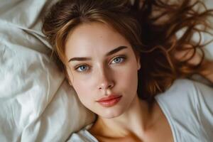 Frau mit lange Haar und Blau Augen Lügen auf Bett suchen beim das Kamera foto