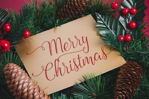 Frohe Weihnachten auf Goldgrußkarte auf grünem Kranz mit Tannenzapfen foto