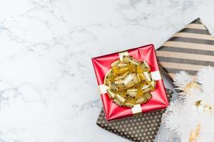 Blick von oben auf die rote glänzende Geschenkbox mit goldener Schleife und Band lag unter dem weißen Weihnachtsbaum
