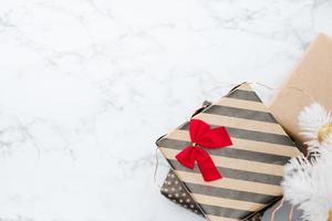 Draufsicht auf moderne gestreifte Geschenkbox mit roter Schleife lag unter weißem Weihnachtsbaum