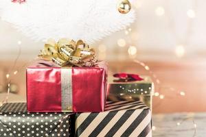 Draufsicht auf moderne gestreifte Geschenkbox mit roter Schleife lag unter weißem Weihnachtsbaum