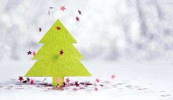 Nahaufnahme grüner Weihnachtsbaum mit funkelnden roten Stern, der auf Weiß fällt foto