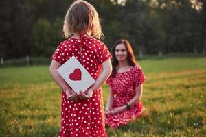 Mutter spielt mit ihrer Tochter auf der Straße im Park bei Sonnenuntergang foto