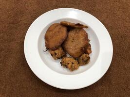 Mirchi pakora oder Mirchi Bhajji serviert im ein Weiß Platte, ein berühmt Mittag Snack im Indien, serviert Über ein rustikal hölzern Hintergrund, selektiv Fokus foto