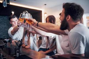 Freizeit- und Kommunikationskonzept. Gruppe glücklicher lächelnder Freunde, die Getränke genießen und sich in der Bar oder im Pub unterhalten foto