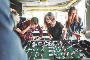 lächelnde junge Leute, die drinnen Tischfußball spielen foto