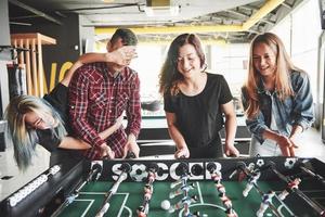 lächelnde junge Leute, die drinnen Tischfußball spielen foto