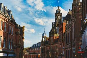 historisch europäisch die Architektur mit ein Uhr Turm unter ein Blau Himmel mit Wolken. alt Gebäude mit kompliziert Einzelheiten im ein Stadtbild im York, Norden Yorkshire, England. foto