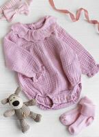 Rosa Bodysuit mit Spielzeug gestrickt Hund, Socken und Stirnband. foto