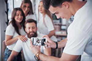 Unschärfeporträt von glückseligen jungen besten Freunden mit den Händen, die das Telefon im Vordergrund halten foto