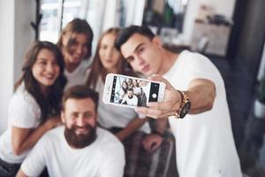 Unschärfeporträt von glückseligen jungen besten Freunden mit den Händen, die das Telefon im Vordergrund halten foto