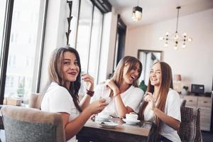 die drei besten Freundinnen versammelten sich, um Kaffee zu trinken und zu klatschen. Mädchen haben Spaß und lachen foto