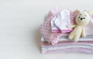 Stapel von Baby Kleidung, Socken und gestrickt Spielzeug foto