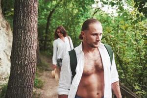 zwei Wanderer mit Rucksäcken auf dem Rücken in der Natur. junges Paar Mann und Frau mögen einen aktiven Urlaub mit einem Zelt, also sind sie an einem sonnigen Tag in die Natur gegangen foto