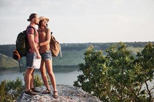 Zwei touristische Männer und Frauen mit Rucksäcken stehen auf dem Gipfel des Berges und genießen den Sonnenaufgang. Reise-Lifestyle-Abenteuer-Urlaub-Konzept foto