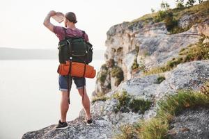 Attraktiver Mann, der den Blick auf die Berglandschaft über der Wasseroberfläche genießt. Reise-Lifestyle-Abenteuer-Urlaub-Konzept foto