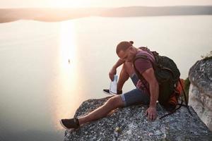 Attraktiver Mann, der den Blick auf die Berglandschaft über der Wasseroberfläche genießt. Reise-Lifestyle-Abenteuer-Urlaub-Konzept foto