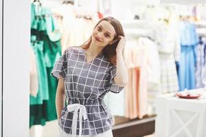 Frau Kleidung einkaufen. Shopper, der sich Kleidung im Innenbereich im Laden ansieht. schönes glückliches lächelndes kaukasisches weibliches Modell