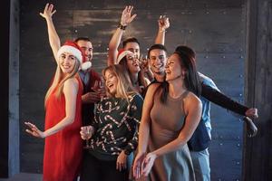 Party mit Freunden. sie lieben weihnachten. Gruppe fröhlicher junger Leute, die Wunderkerzen und Champagnerflöten tragen, die in der Neujahrsparty tanzen und glücklich aussehen. Konzepte zum Zusammengehörigkeitsleben foto