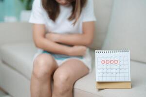 Menstruation Zeitraum Zyklus von monatlich und Magenschmerzen Konzepte. Frau haben Abdomen Schmerzen mit heiß Wasser Flasche und Kalender, Krankheit weiblich leiden von prämenstruell schmerzen und Körper Gesundheit Problem foto