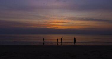 Silhouetten Strand Abend glühen mit Menschen Aktivität und Gehen durch das Meer foto