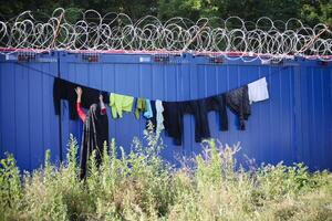 gewaschen Kleider Trocknen unten mit Widerhaken Kabel. herausfordernd Leben Bedingungen im ein improvisiert Transit Flüchtling Lager beim das serbisch und ungarisch Grenze. foto