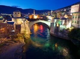 Nacht Aussicht von das alt Brücke im Mostar Stadt im Bosnien und Herzegowina. Neretva Fluss. UNESCO Welt Erbe Seite? ˅. Menschen Gehen Über das Brücke. foto