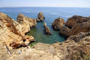 Menschen genießen ein sonnig Sommer- Tag beim das magisch ponta da Piedade im das Süd von Portugal, Algarve. Boote auf das Bucht zu erkunden das Höhlen und Tunnel im das Ozean. foto