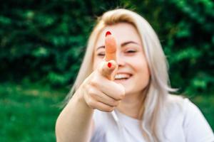 Frau lächelt, macht Schuss von Fingern in die Kamera mit glücklichem Gesicht foto