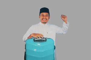 Moslem asiatisch Mann Tragen Koffer mit aufgeregt Ausdruck foto