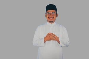 Moslem asiatisch Mann lächelnd beim das Kamera mit Hand Respekt oder Gruß Pose foto