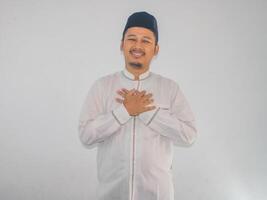 Moslem asiatisch Mann lächelnd glücklich mit beide Hand auf seine Truhe foto