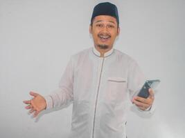 Moslem asiatisch Mann zeigen erstaunt Ausdruck während halten Handy, Mobiltelefon Telefon foto