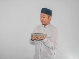 Moslem asiatisch Mann lächelnd glücklich während halten leeren Abendessen Teller foto