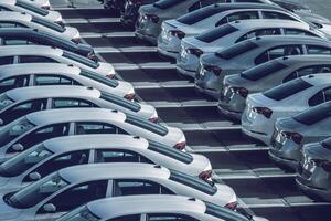 Reihen von ein Neu Autos geparkt im ein Verteilung Center auf ein Auto Fabrik auf ein sonnig Tag. oben Aussicht zu das Parken. foto