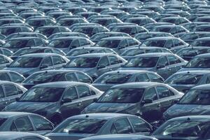 Reihen von ein Neu Autos geparkt im ein Verteilung Center auf ein Auto Fabrik auf ein sonnig Tag. oben Aussicht zu das Parken. foto