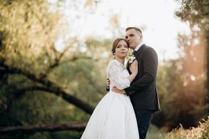 Der Bräutigam und die Braut gehen im Wald in der Nähe eines schmalen Flusses spazieren foto