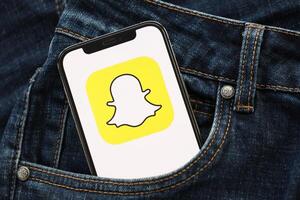 Kiew, Ukraine - - April 1, 2024 Snapchat Symbol auf Smartphone Anzeige Bildschirm im Jeans Tasche foto