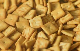 Viele kleine Kekse sind quadratisch. ein Muster eines gelben Salzcrackers. Hintergrundbild mit Salzgebäck foto